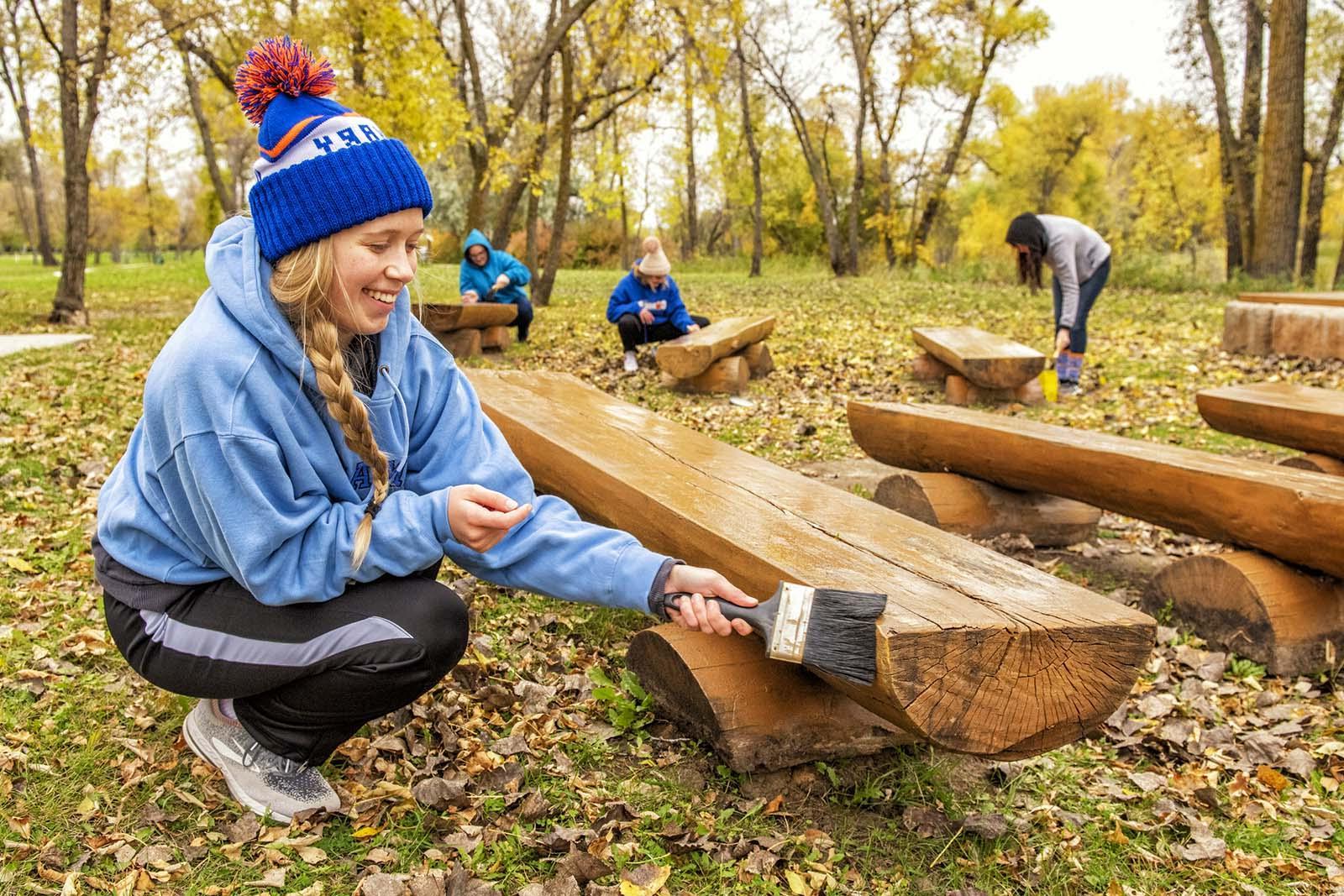 Student painting a bench during Day of Service